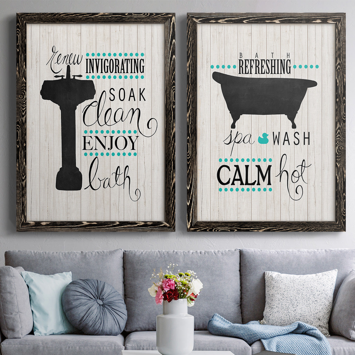 Set of two black barnwood framed canvas prints depicting paired graphic bathroom word art with black tubs, hand-lettered phrases, and small teal accents above a sofa in a contemporary living room.