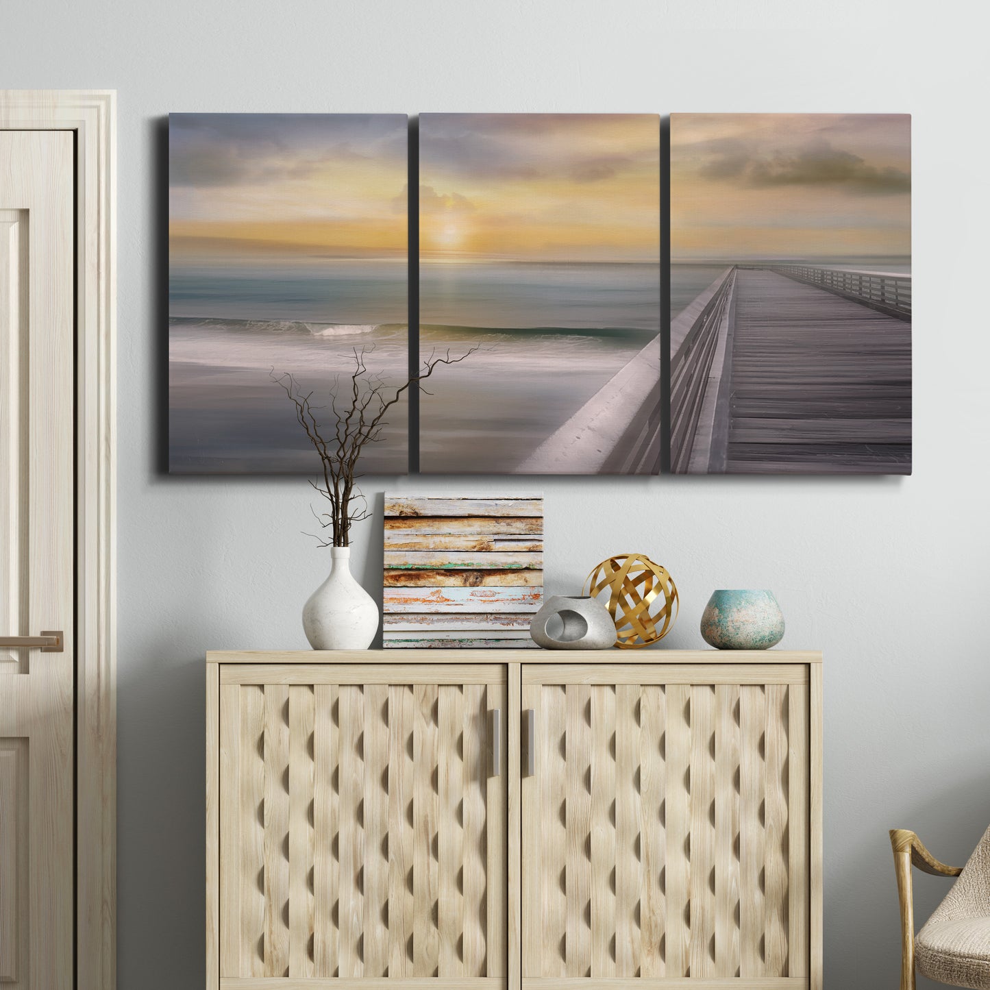 Three-panel canvas wall art featuring tropical beach at sunset photograph, displayed above a cabinet in an entryway.