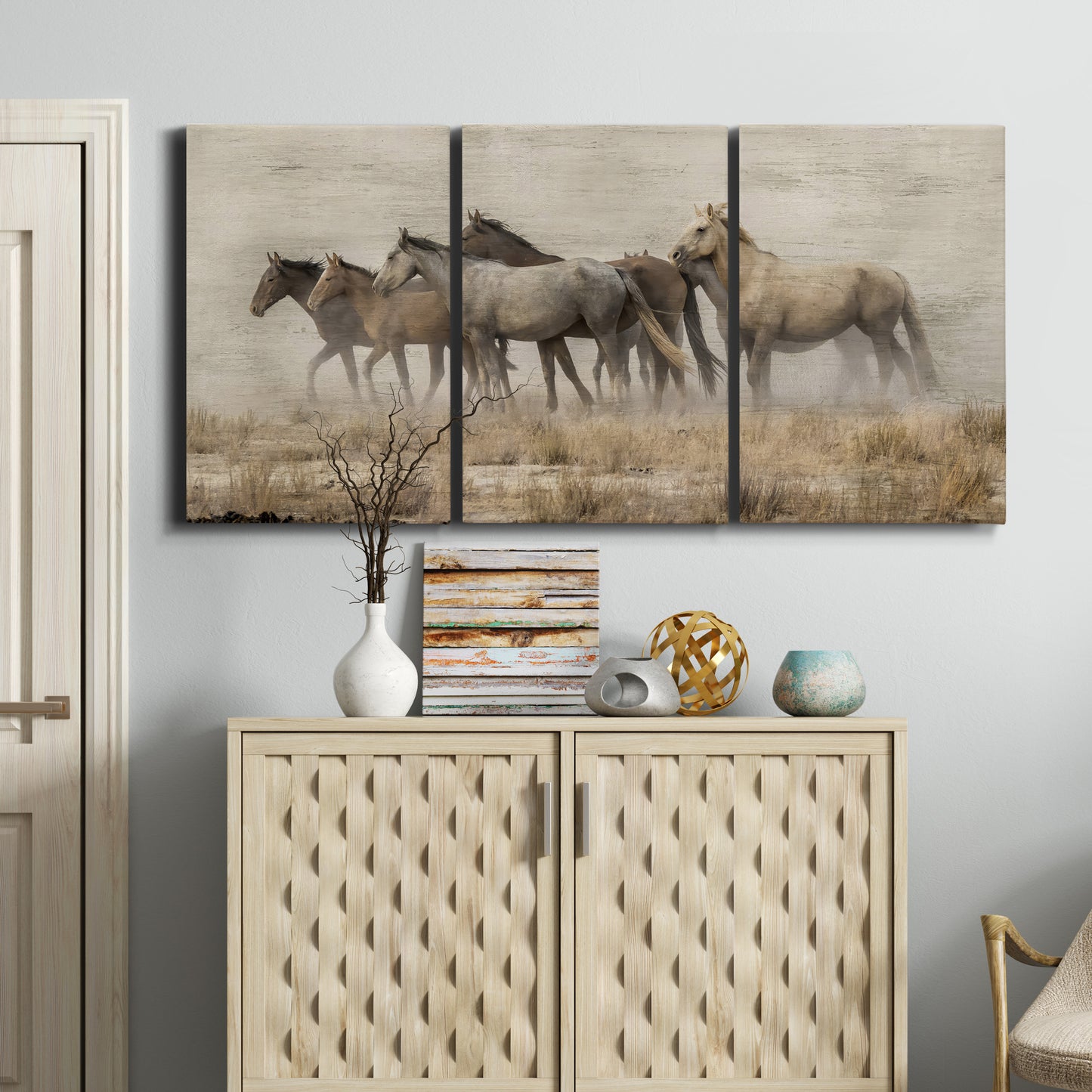 Three-panel canvas wall art featuring wild horses roaming open terrain, displayed above a cabinet in an entryway.