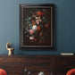 Classical floral still life painting by Jan van Huysum in an ornate black frame with gilded inner detail displayed in a dark-toned interior setting.