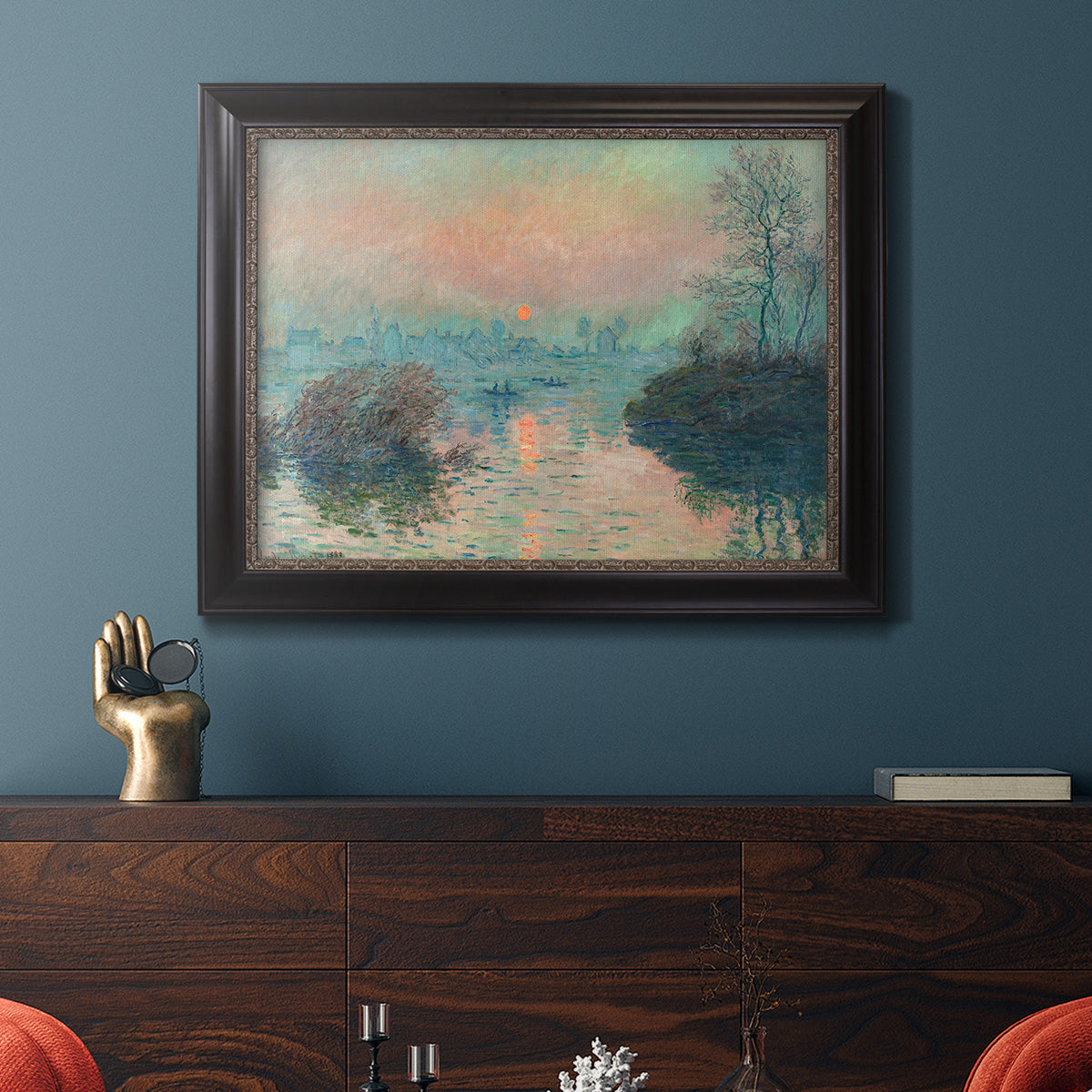 Impressionist winter river sunset scene by Claude Monet in an ornate black frame with gilded inner detail displayed in a dark-toned interior setting.