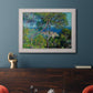Impressionist Mediterranean coastal landscape by Claude Monet in an ornate weathered white frame displayed in a dark-toned interior setting.