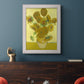 Impressionist sunflower still life painting by Vincent van Gogh in an ornate weathered white frame displayed in a dark-toned interior setting.