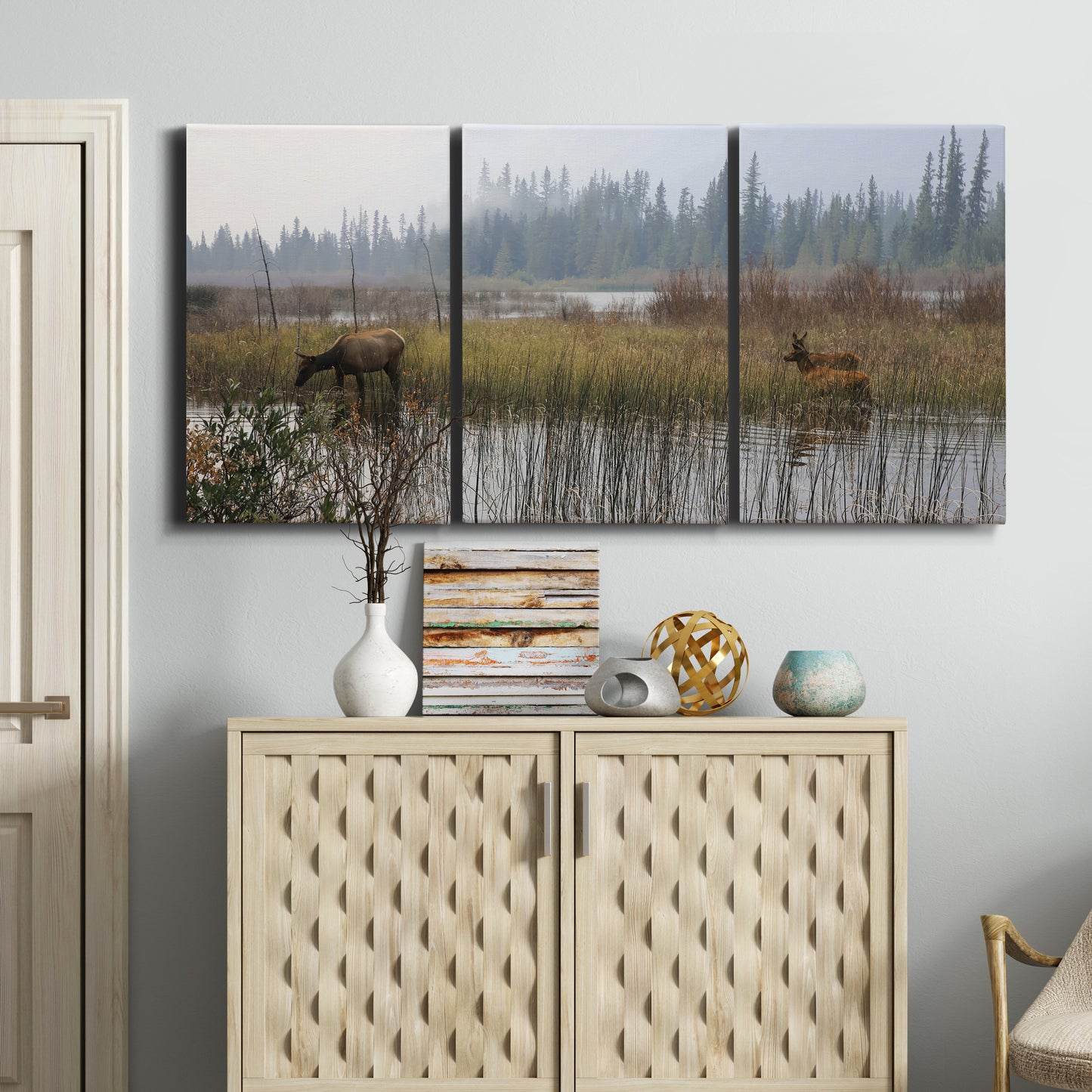 Three-panel canvas wall art featuring wildlife walking through open field, displayed above a cabinet in an entryway.