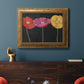 Contemporary poppy flower artwork in an ornate vintage gold frame displayed in a dark-toned interior setting.