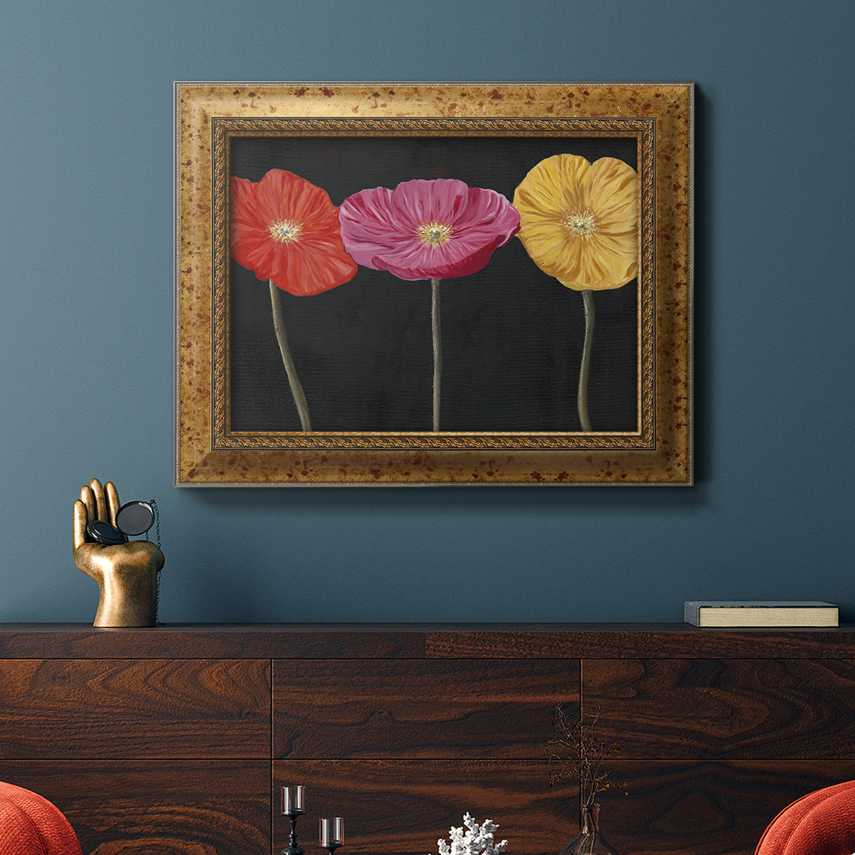 Contemporary poppy flower artwork in an ornate vintage gold frame displayed in a dark-toned interior setting.