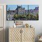 Three-panel canvas wall art featuring gothic church within city setting, displayed above a cabinet in an entryway.
