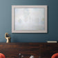 Impressionist atmospheric landscape in morning haze by Claude Monet in an ornate weathered white frame displayed in a dark-toned interior setting.