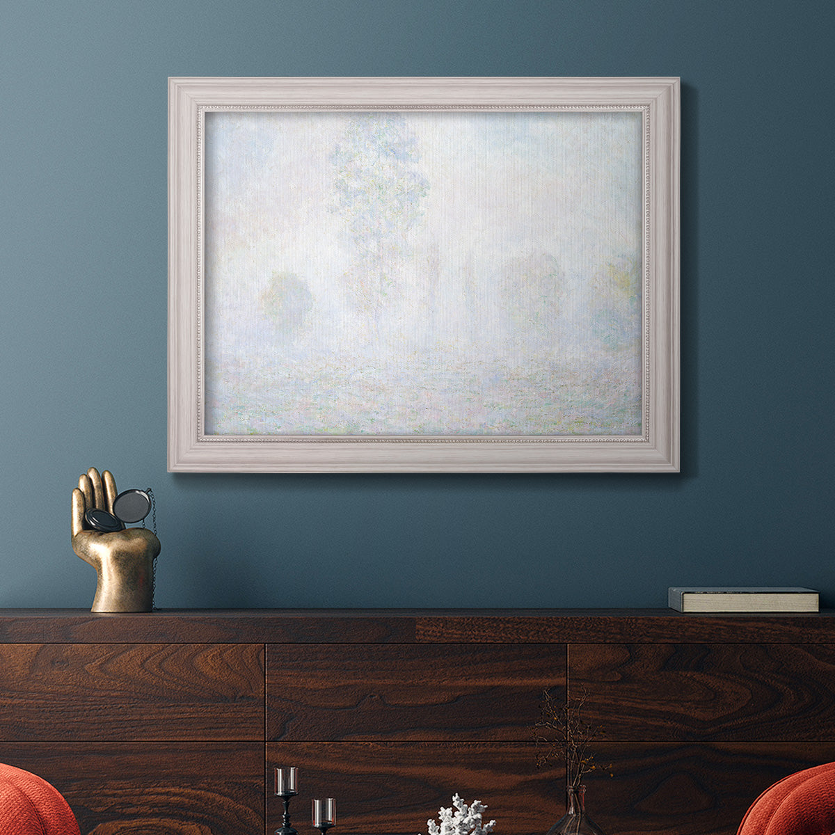Impressionist atmospheric landscape in morning haze by Claude Monet in an ornate weathered white frame displayed in a dark-toned interior setting.