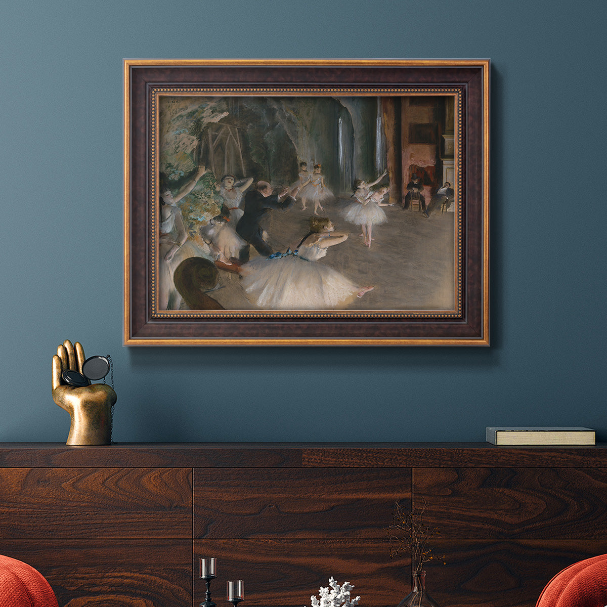 Impressionist backstage ballet scene by Edgar Degas in an ornate bronzed mahogany wood frame displayed in a dark-toned interior setting.