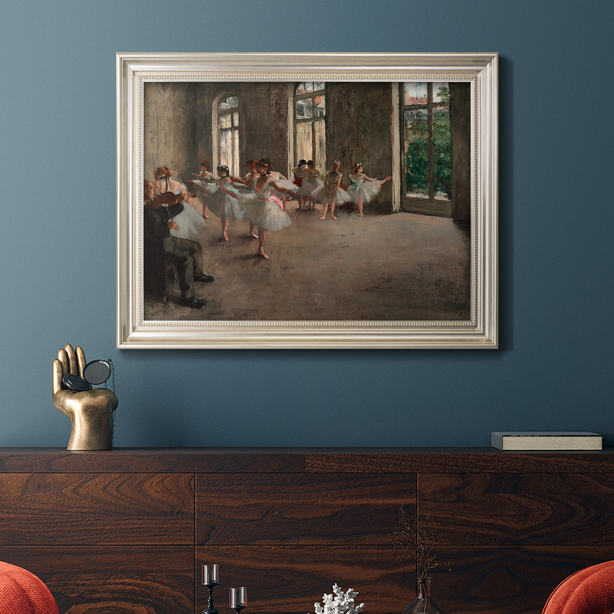 Early impressionist ballet rehearsal painting by Edgar Degas in an ornate champagne frame displayed in a dark-toned interior setting.