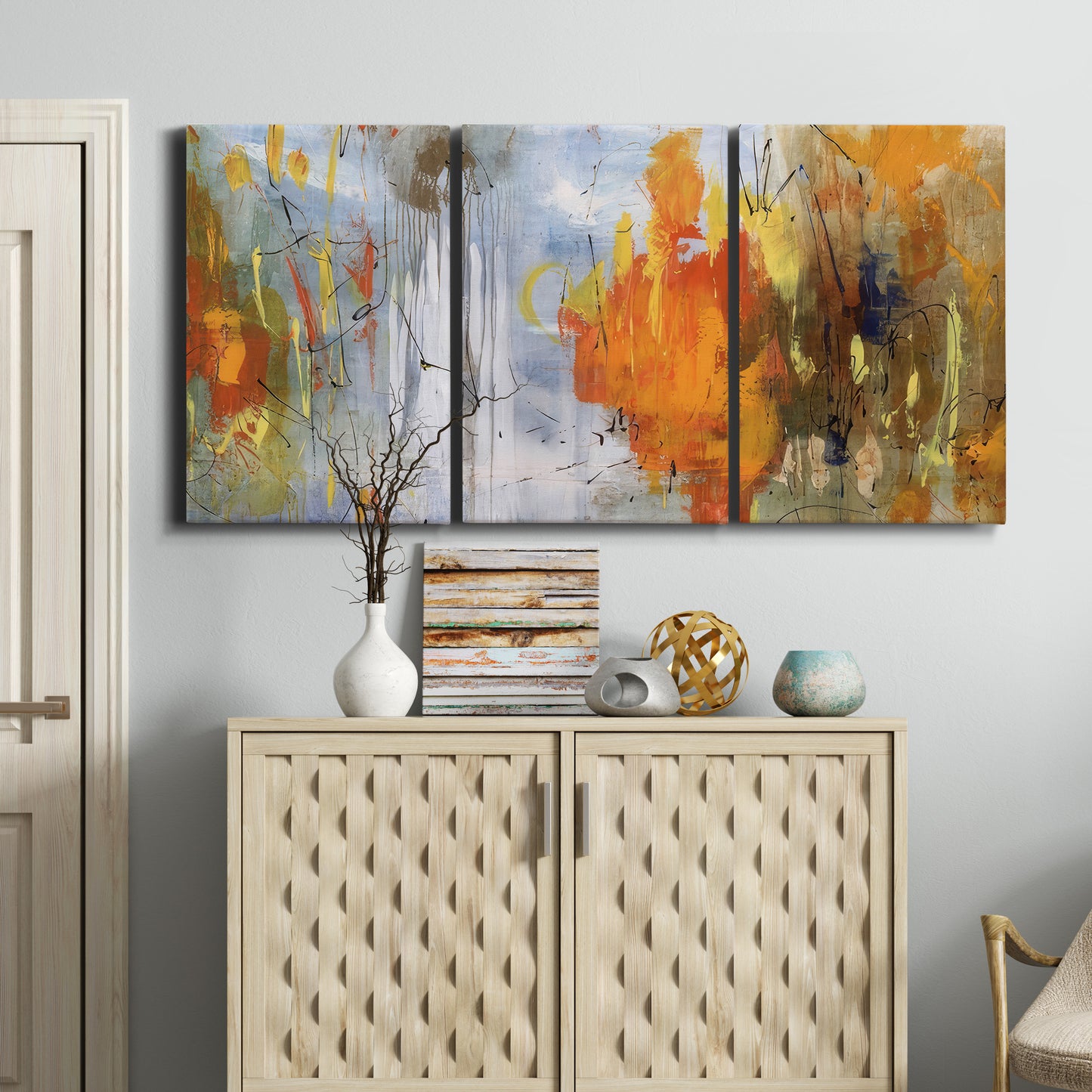 Three-panel canvas wall art featuring abstract warm sunset tones, displayed above a cabinet in an entryway.