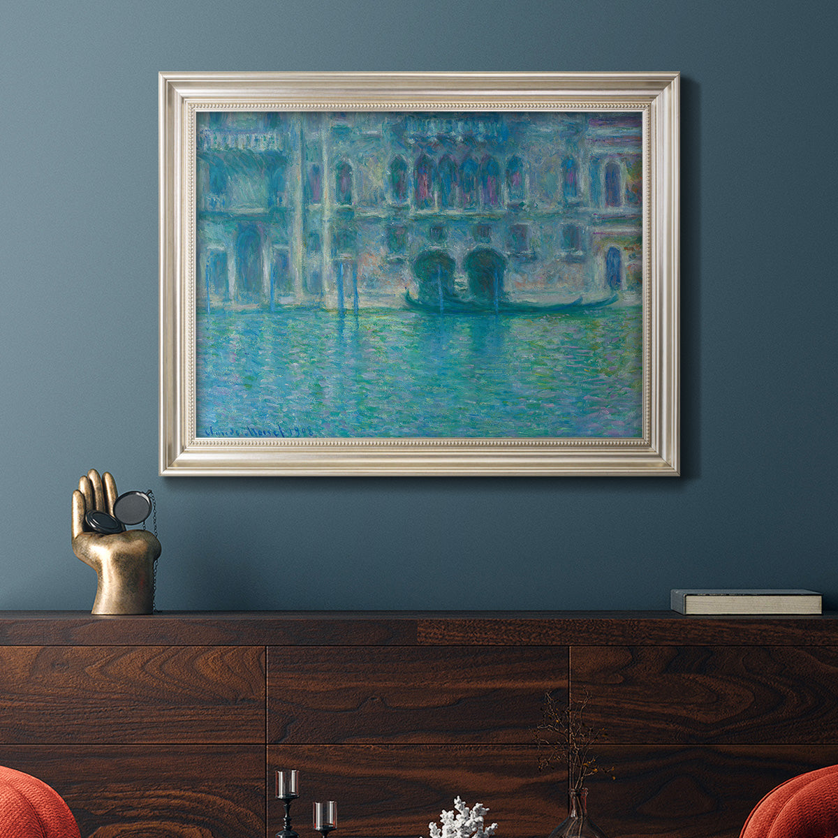 Impressionist Venetian palace waterfront scene by Claude Monet in an ornate champagne frame displayed in a dark-toned interior setting.