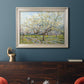 Impressionist white-blossomed orchard landscape by Vincent van Gogh in an ornate champagne frame displayed in a dark-toned interior setting.