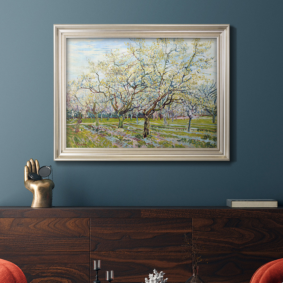 Impressionist white-blossomed orchard landscape by Vincent van Gogh in an ornate champagne frame displayed in a dark-toned interior setting.