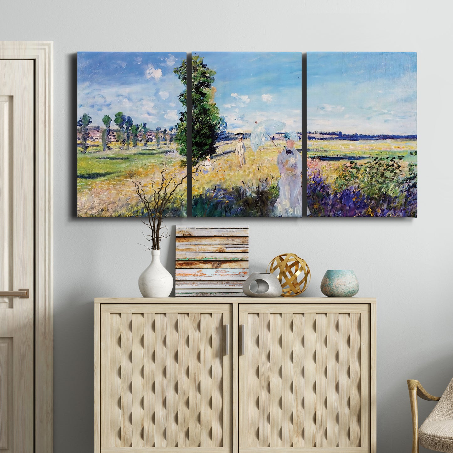 Three-panel canvas wall art featuring riverside path with figures, displayed above a cabinet in an entryway.