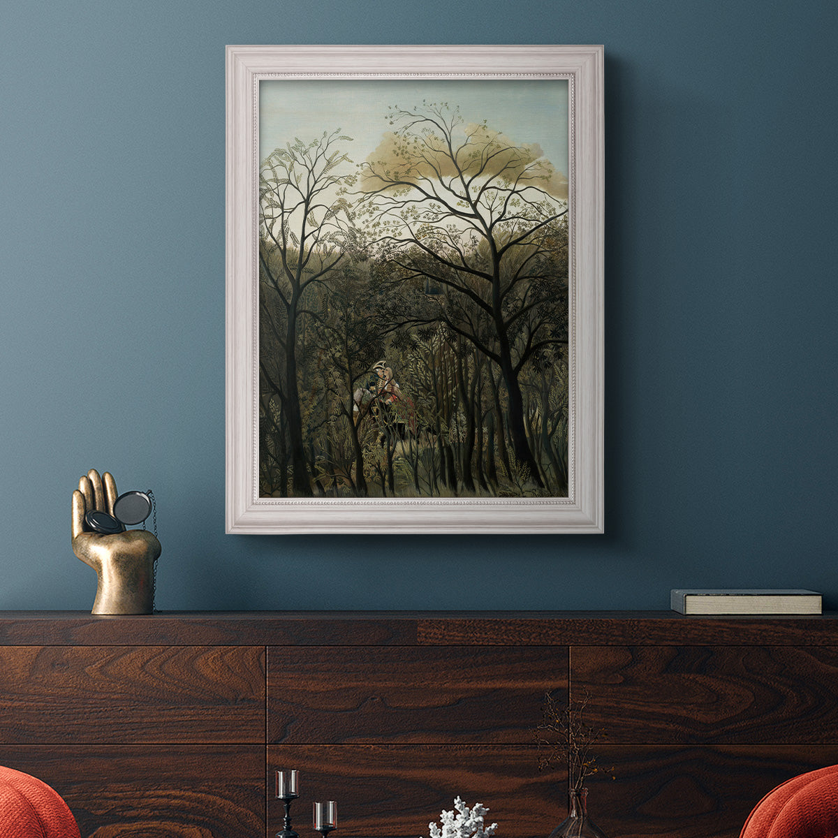 Dreamlike forest landscape scene by Henri Rousseau in an ornate weathered white frame displayed in a dark-toned interior setting.