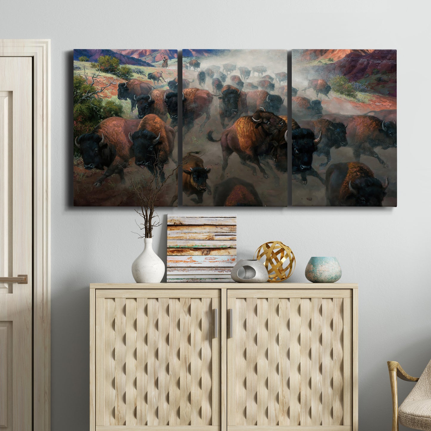 Three-panel canvas wall art featuring stormy canyon landscape with animals, displayed above a cabinet in an entryway.