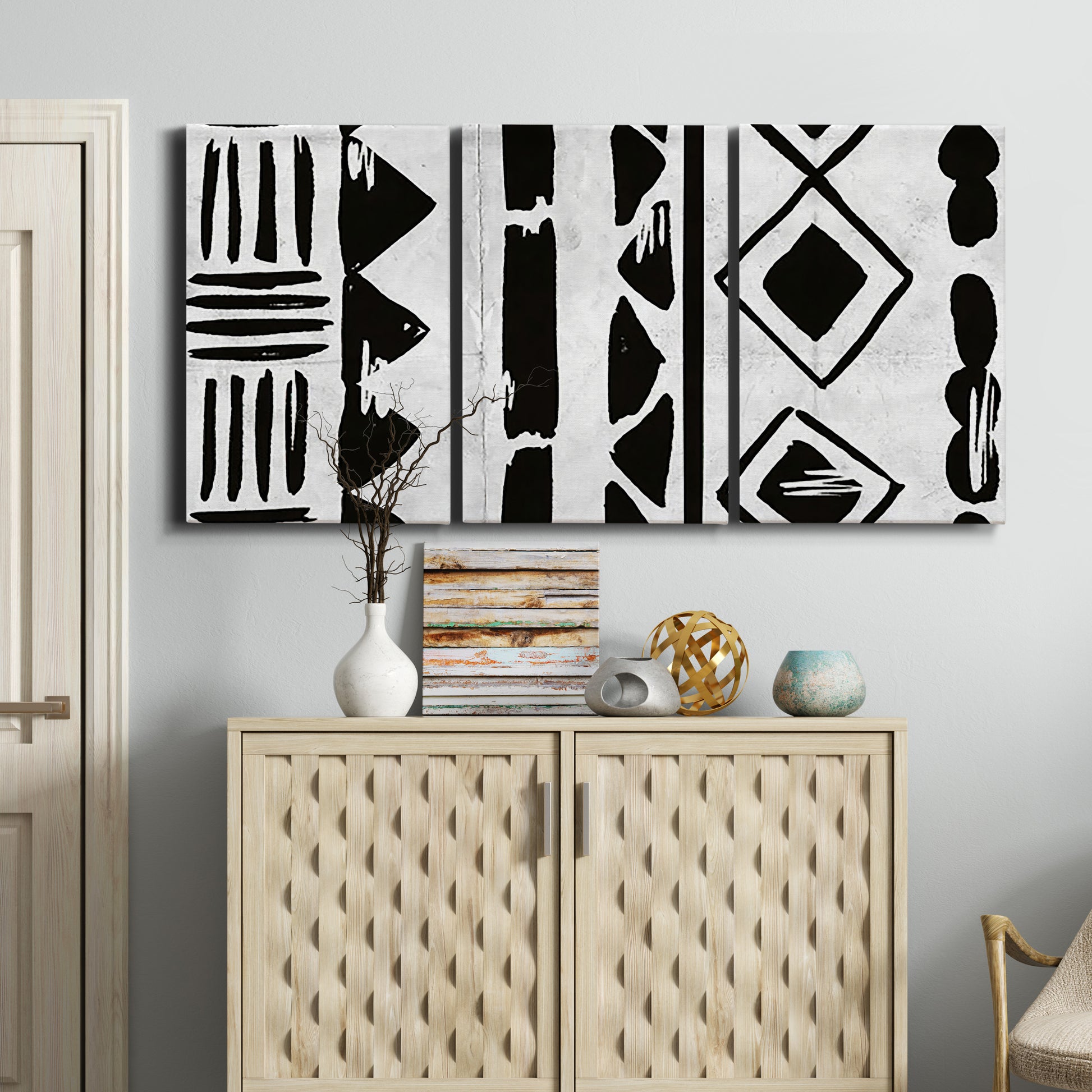 Three-panel canvas wall art featuring geometric abstract forms merging pattern, displayed above a cabinet in an entryway.