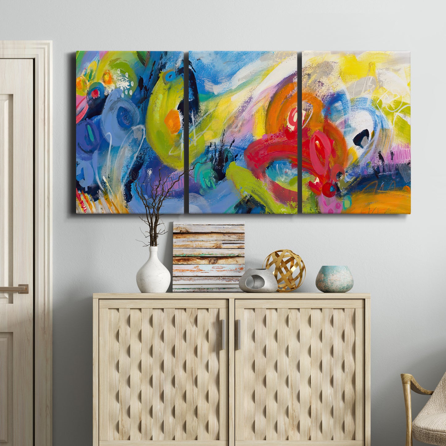 Three-panel canvas wall art featuring colorful abstract racing forms, displayed above a cabinet in an entryway.
