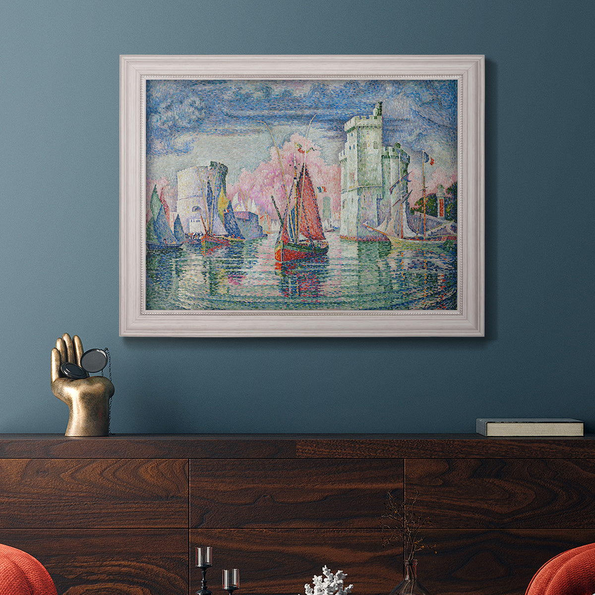 Impressionist harbor scene by Paul Signac in an ornate weathered white frame displayed in a dark-toned interior setting.