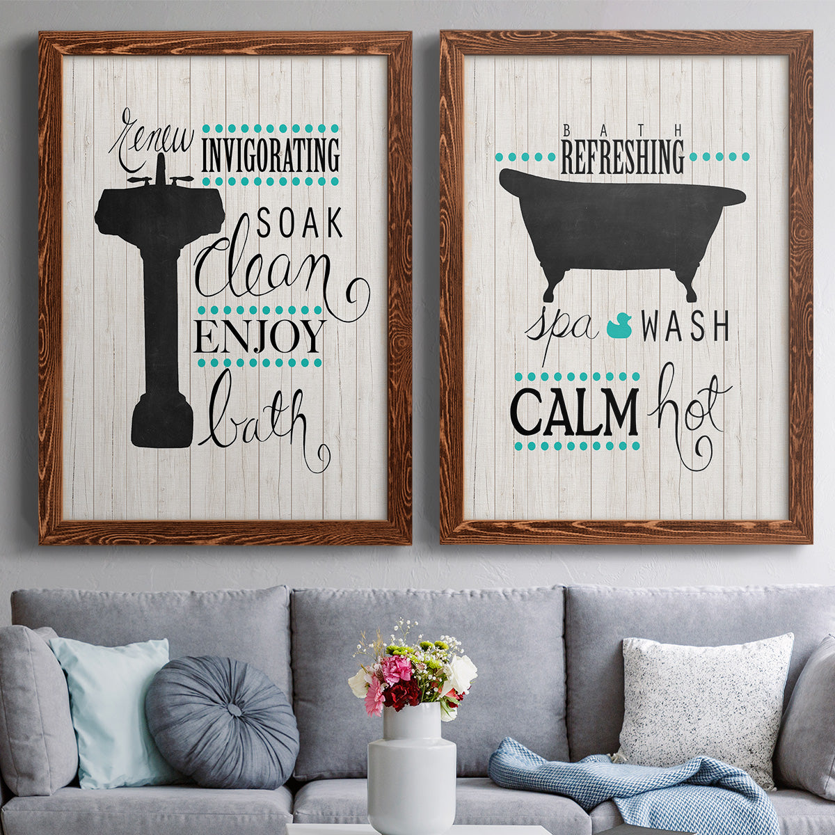 Set of two maple barnwood framed canvas prints depicting paired graphic bathroom word art with black tubs, hand-lettered phrases, and small teal accents above a sofa in a contemporary living room.