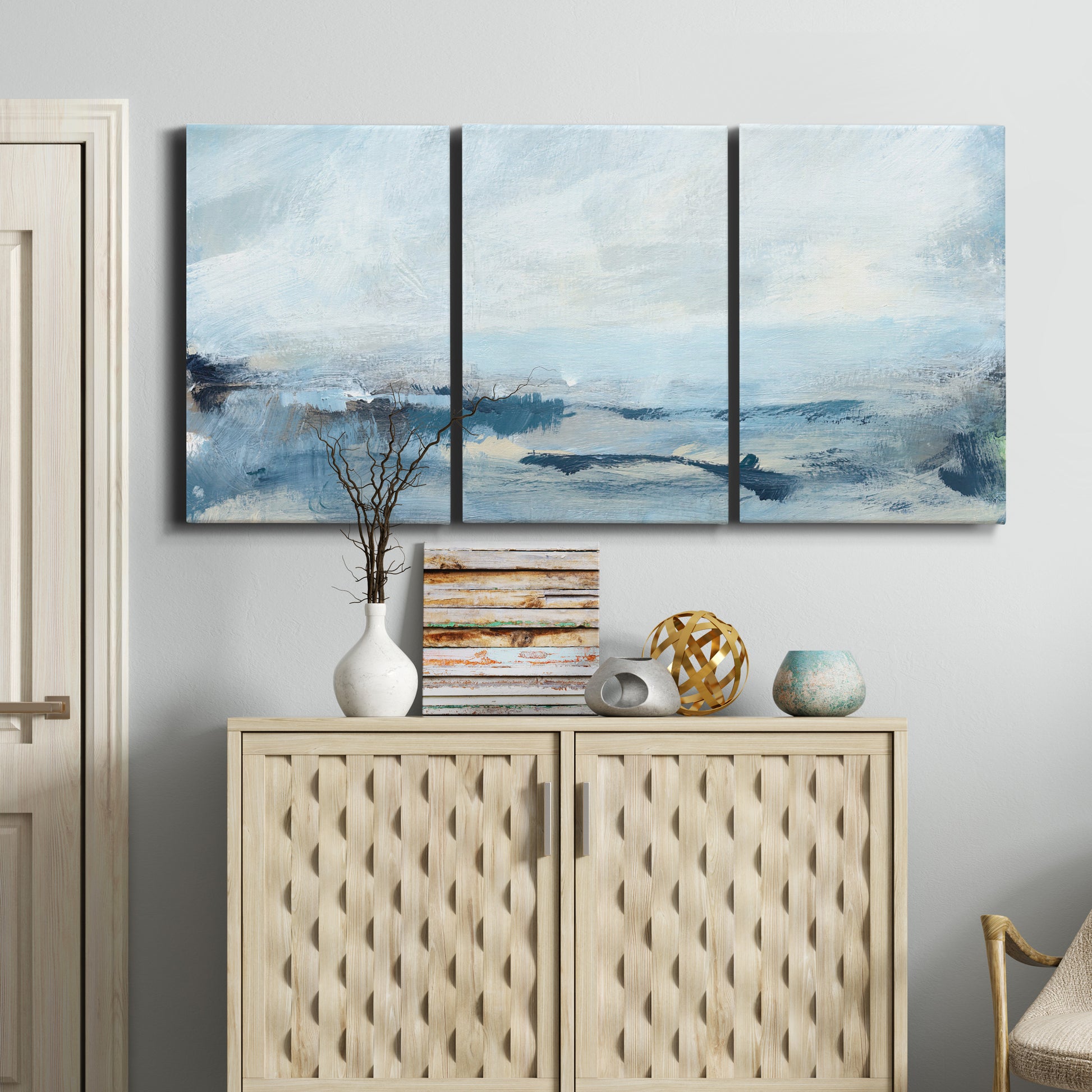 Three-panel canvas wall art featuring abstract sailboats on water, displayed above a cabinet in an entryway.