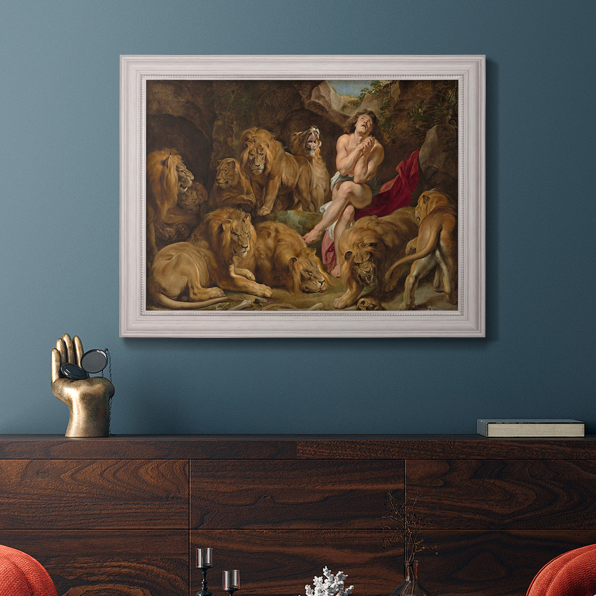 Dramatic biblical painting of Daniel with lions by Peter Paul Rubens in an ornate weathered white frame displayed in a dark-toned interior setting.