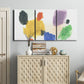 Three-panel canvas wall art featuring inkblot style abstract color symmetry, displayed above a cabinet in an entryway.