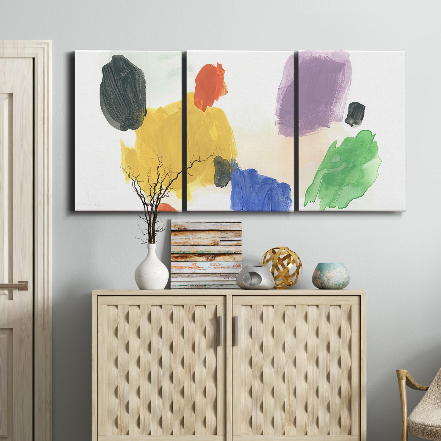 Three-panel canvas wall art featuring inkblot style abstract color symmetry, displayed above a cabinet in an entryway.