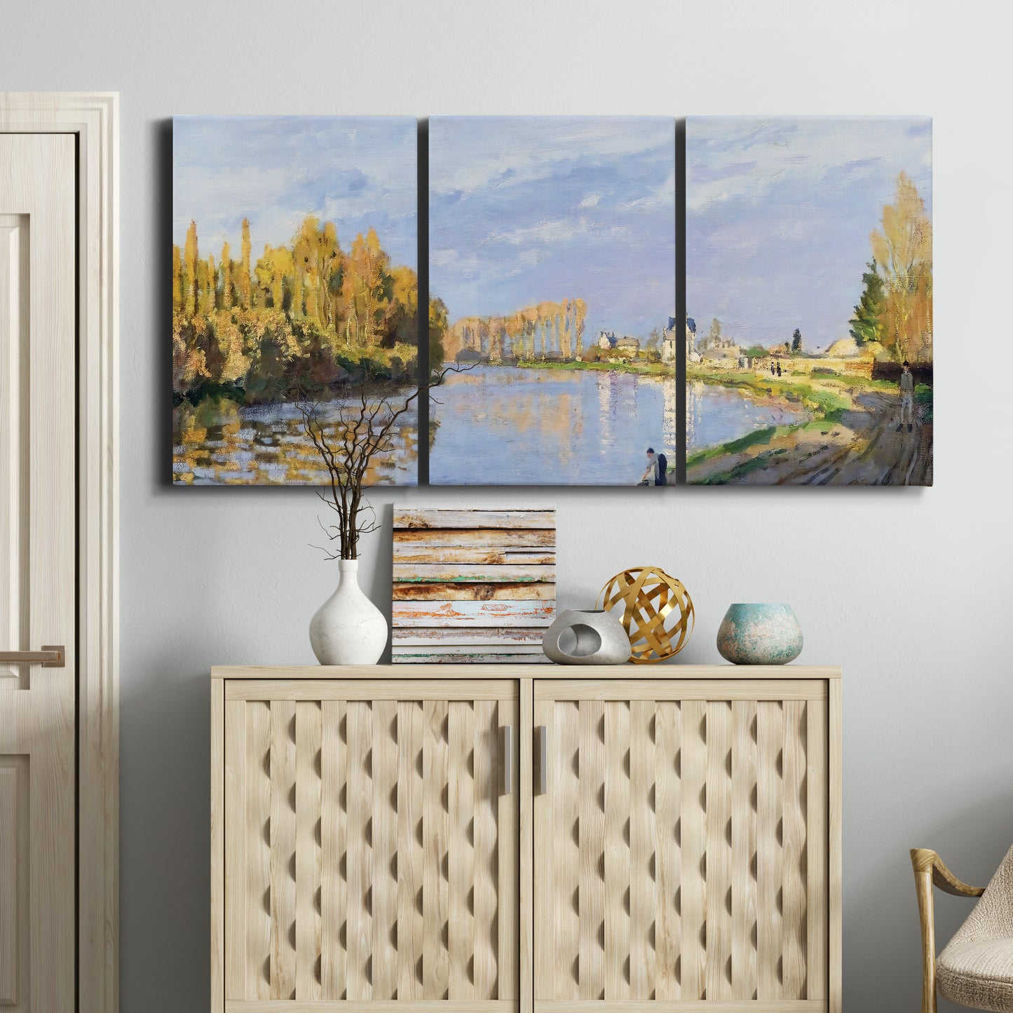 Three-panel canvas wall art featuring river flowing past village, displayed above a cabinet in an entryway.