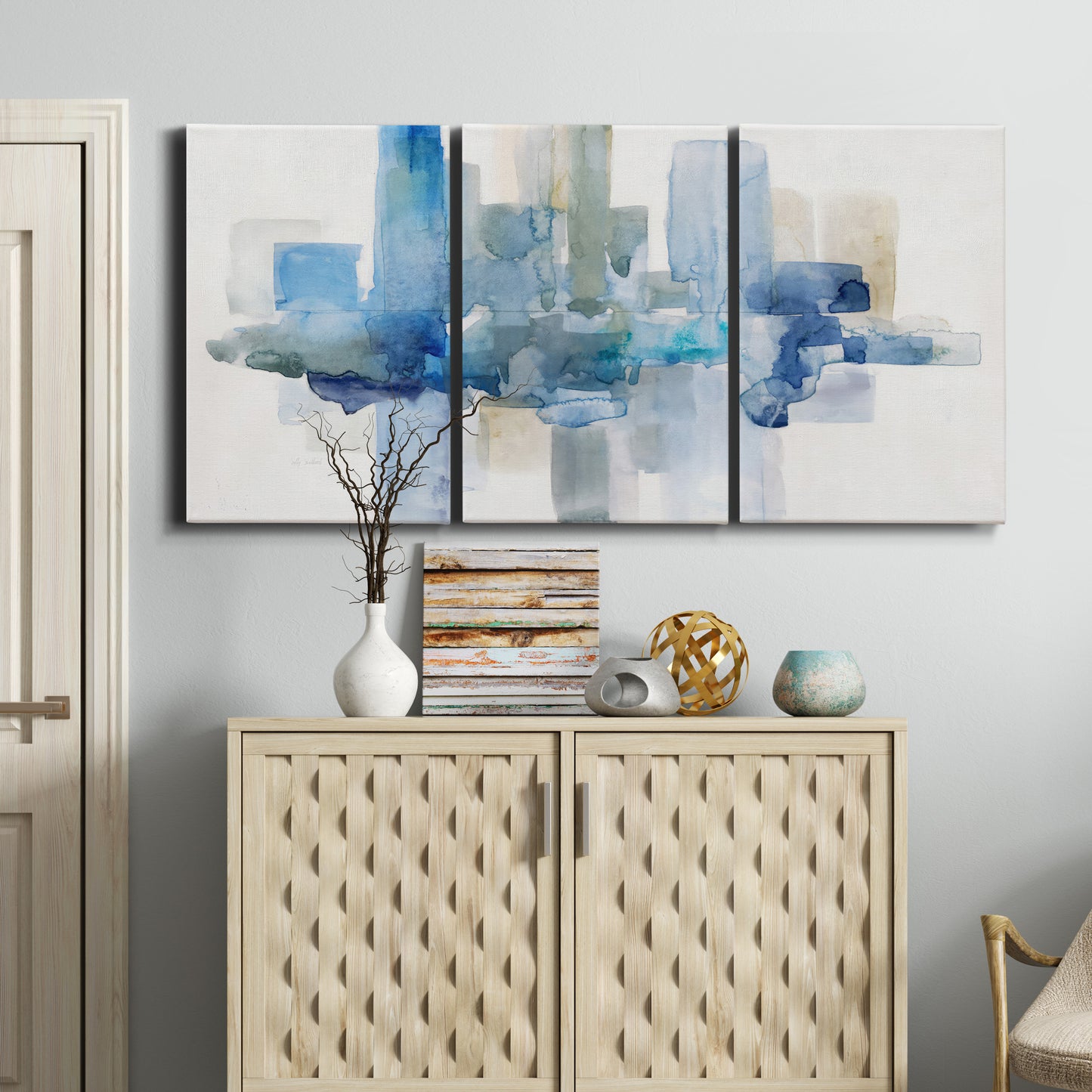 Three-panel canvas wall art featuring minimal urban skyline watercolor, displayed above a cabinet in an entryway.