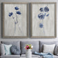 Set of two gray barnwood framed canvas prints depicting paired rustic monochrome botanical paintings with indigo blossoms, thin stems, and softly distressed gray backgrounds above a sofa in a contemporary living room.