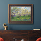 Impressionist spring orchard landscape by Vincent van Gogh in an ornate bronzed mahogany wood frame displayed in a dark-toned interior setting.