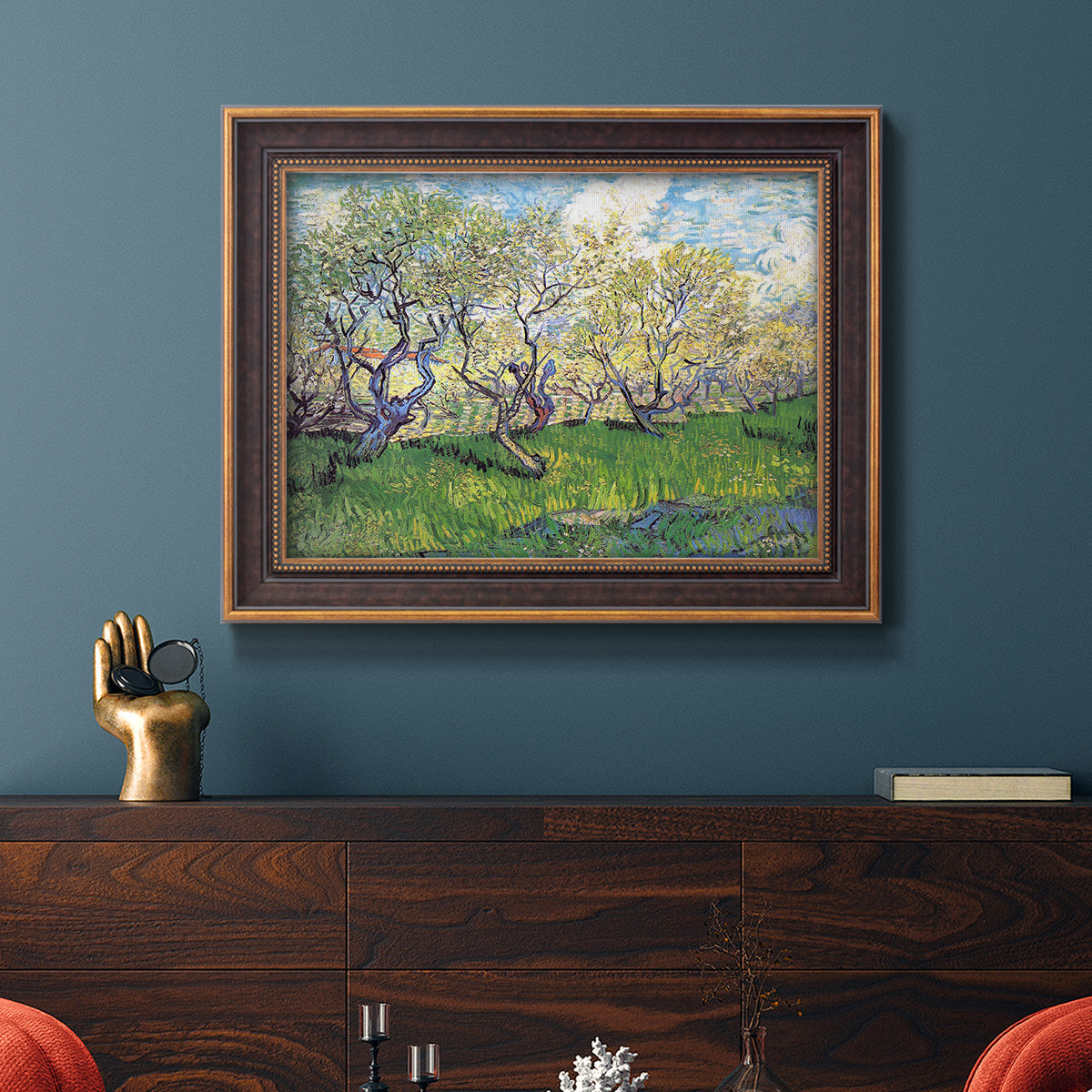 Impressionist spring orchard landscape by Vincent van Gogh in an ornate bronzed mahogany wood frame displayed in a dark-toned interior setting.