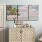 Three-panel canvas wall art featuring tropical sand dunes with palms, displayed above a cabinet in an entryway.