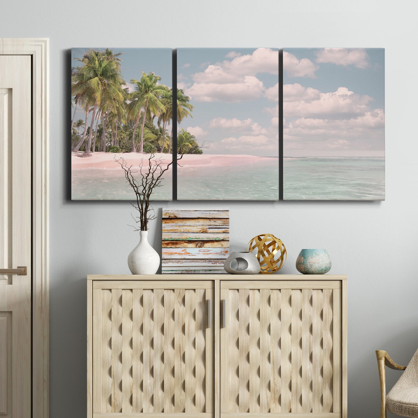 Three-panel canvas wall art featuring tropical sand dunes with palms, displayed above a cabinet in an entryway.