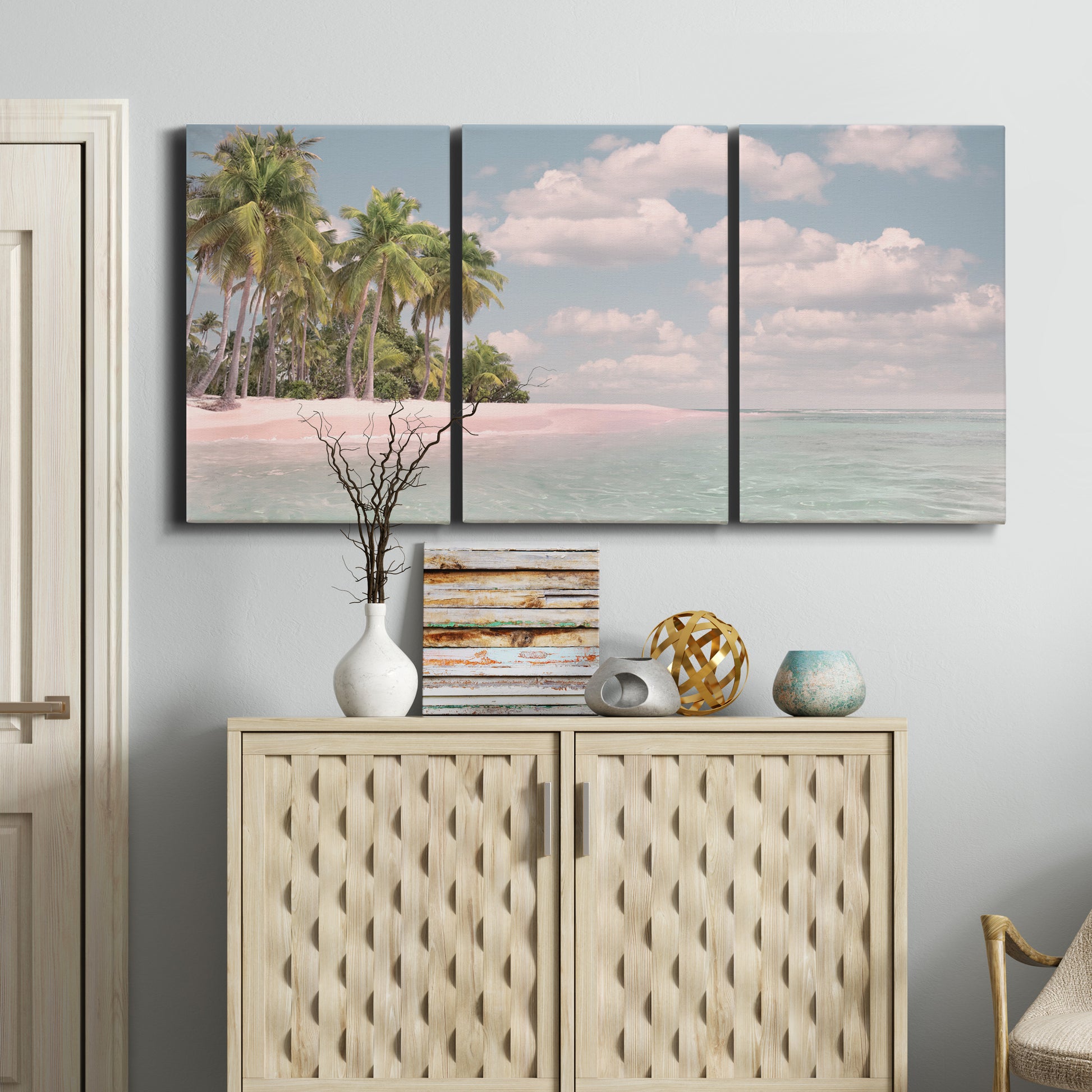 Three-panel canvas wall art featuring tropical sand dunes with palms, displayed above a cabinet in an entryway.
