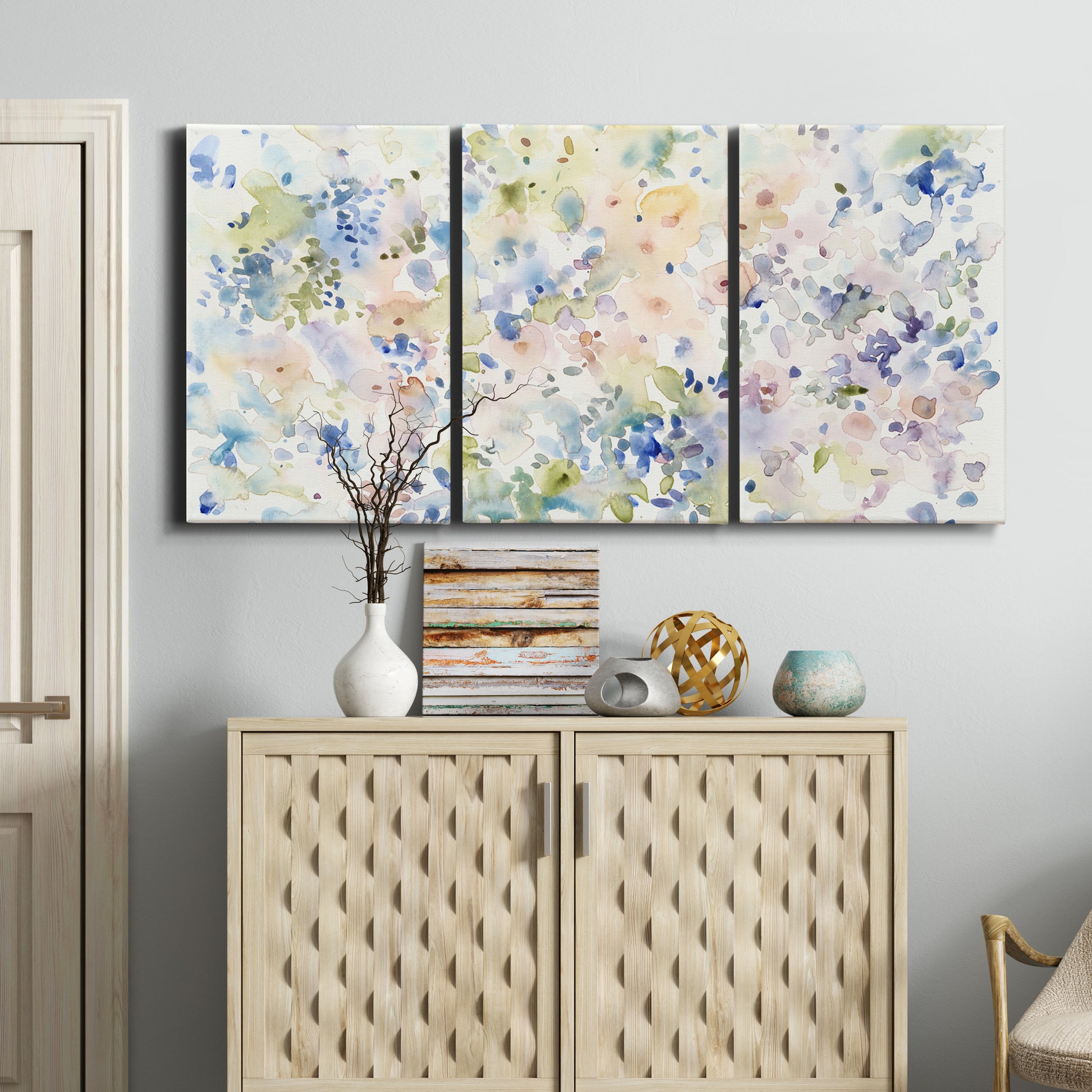 Three-panel canvas wall art featuring flowing abstract watercolor, displayed above a cabinet in an entryway.