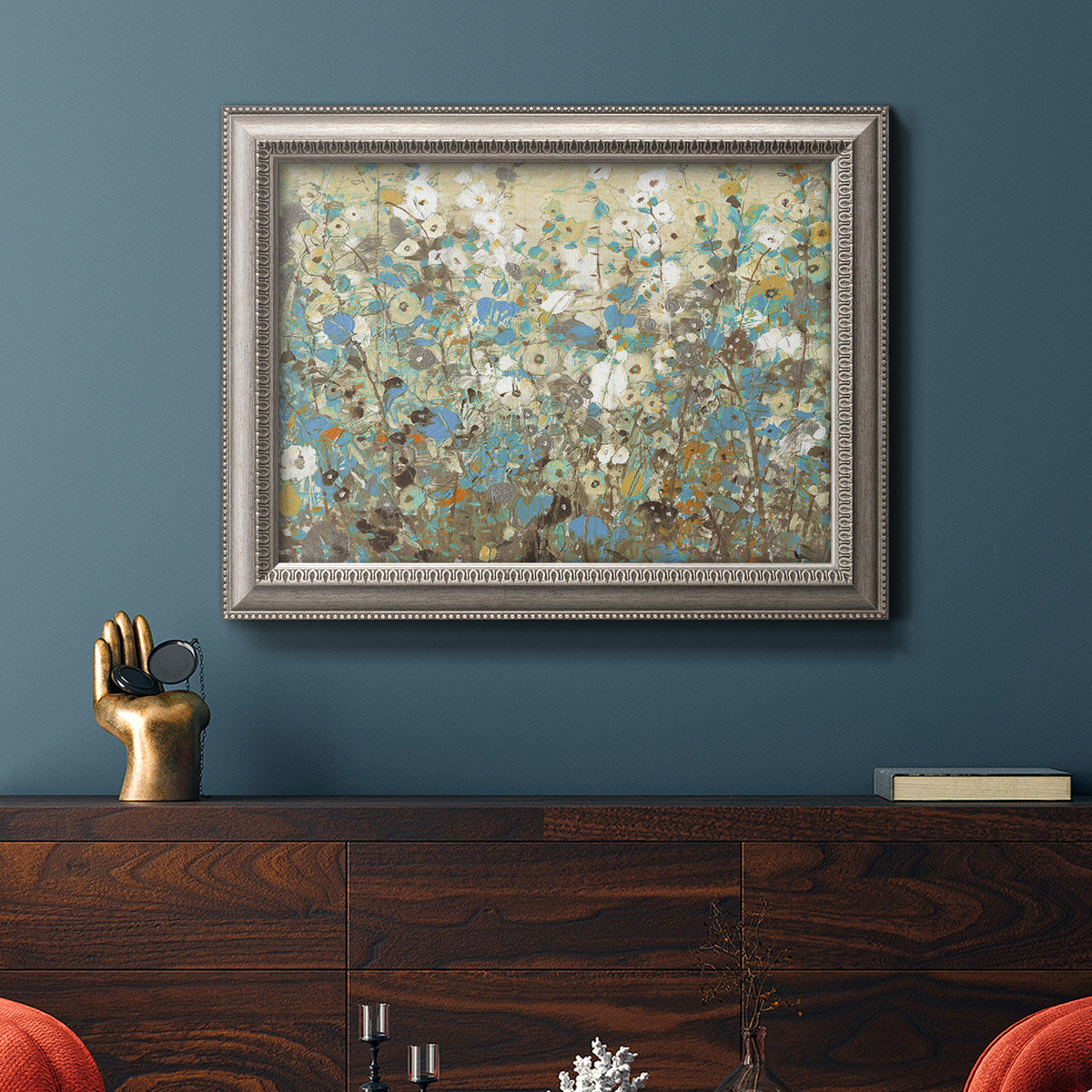 Impressionist flowering vine watercolor artwork in an ornate vintage silver frame displayed in a dark-toned interior setting.