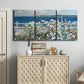 Three-panel canvas wall art featuring coastal garden overlooking bay, displayed above a cabinet in an entryway.