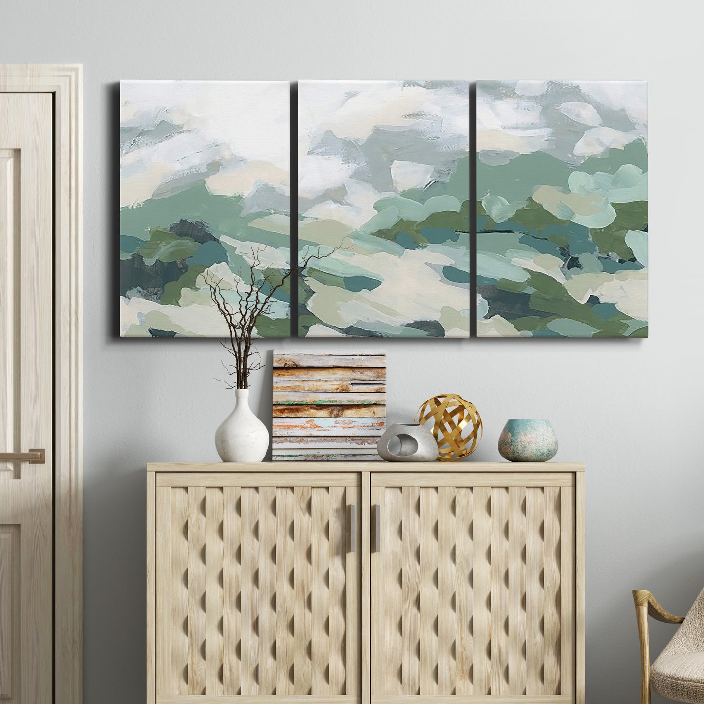 Three-panel canvas wall art featuring lush green hillside rolling landscape, displayed above a cabinet in an entryway.