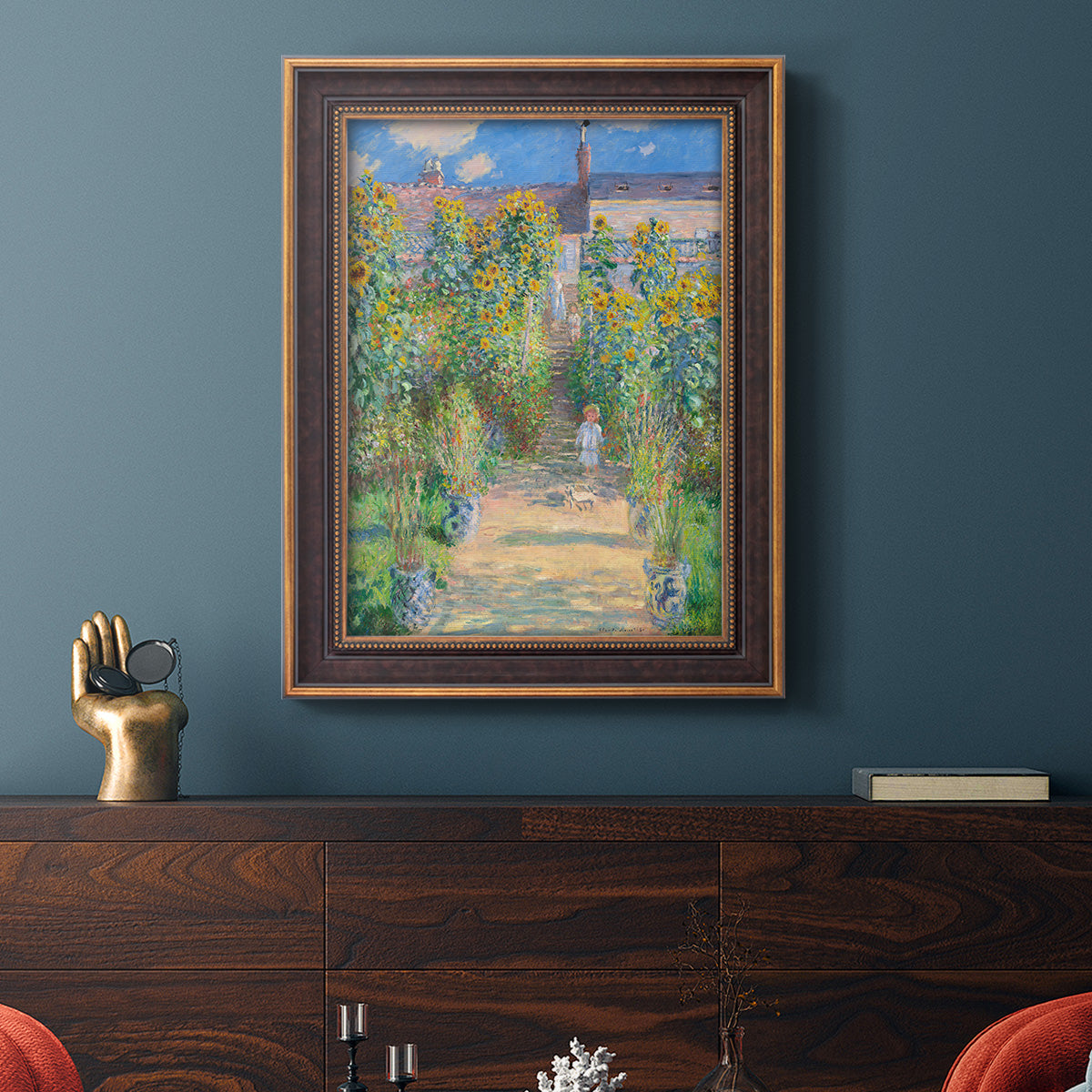 Impressionist garden landscape painting by Claude Monet in an ornate bronzed mahogany wood frame displayed in a dark-toned interior setting.
