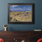 Impressionist wheat harvest scene by Vincent van Gogh in an ornate black frame with gilded inner detail displayed in a dark-toned interior setting.