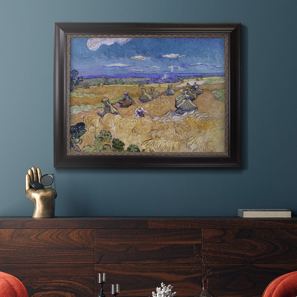 Impressionist wheat harvest scene by Vincent van Gogh in an ornate black frame with gilded inner detail displayed in a dark-toned interior setting.
