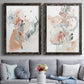 Set of two black barnwood framed canvas prints depicting paired abstract watercolor botanicals with scribbled petals, translucent washes, and drifting stems above a sofa in a contemporary living room.