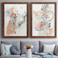 Set of two maple barnwood framed canvas prints depicting paired abstract watercolor botanicals with scribbled petals, translucent washes, and drifting stems above a sofa in a contemporary living room.