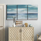 Three-panel canvas wall art featuring calm coastal shoreline, displayed above a cabinet in an entryway.