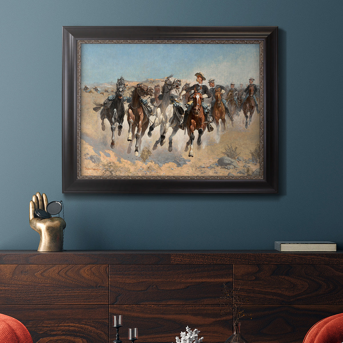 Impressionist western action scene by Frederic Remington in an ornate black frame with gilded inner detail displayed in a dark-toned interior setting.
