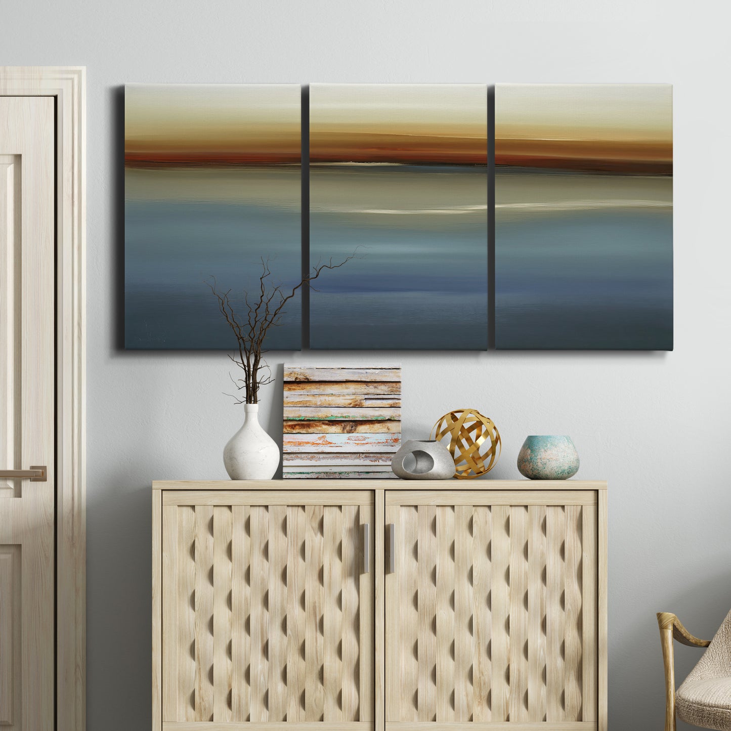 Three-panel canvas wall art featuring horizontal abstract coastal color bands, displayed above a cabinet in an entryway.